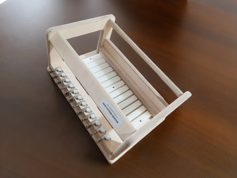 May include: A wooden soap cutter crafter with a white plastic cutting surface and 10 metal cutting blades. The text "SOAP CUTTER CRAFTERS" is printed on the side of the cutter.