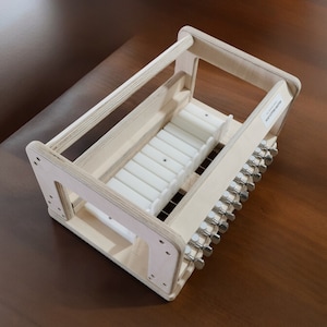 May include: A wooden frame with a white plastic insert and metal knobs. The frame is designed to hold and organize small items.