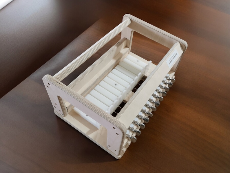 May include: A wooden frame with a white plastic insert and metal knobs. The frame is designed to hold and organize small items.