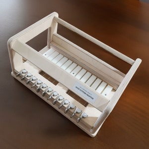 May include: A wooden soap cutter crafter with a white label that reads "ALL SOAP SIZES 1-2 SOAP CUTTER CRAFTERS". The cutter has a series of metal blades and a wooden frame.