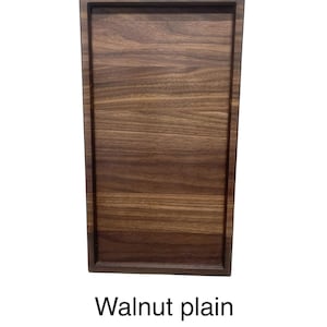 May include: A rectangular walnut serving tray with a raised border. The wood grain is visible, showcasing a natural brown color. The text "Walnut plain" is printed at the bottom of the image.