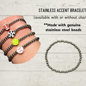 May include: Stainless steel accent bracelets with sports-themed charms. The bracelets feature a football, soccer ball, tennis ball, and baseball charm. The text reads "STAINLESS ACCENT BRACELET" and "Made with genuine stainless steel beads."
