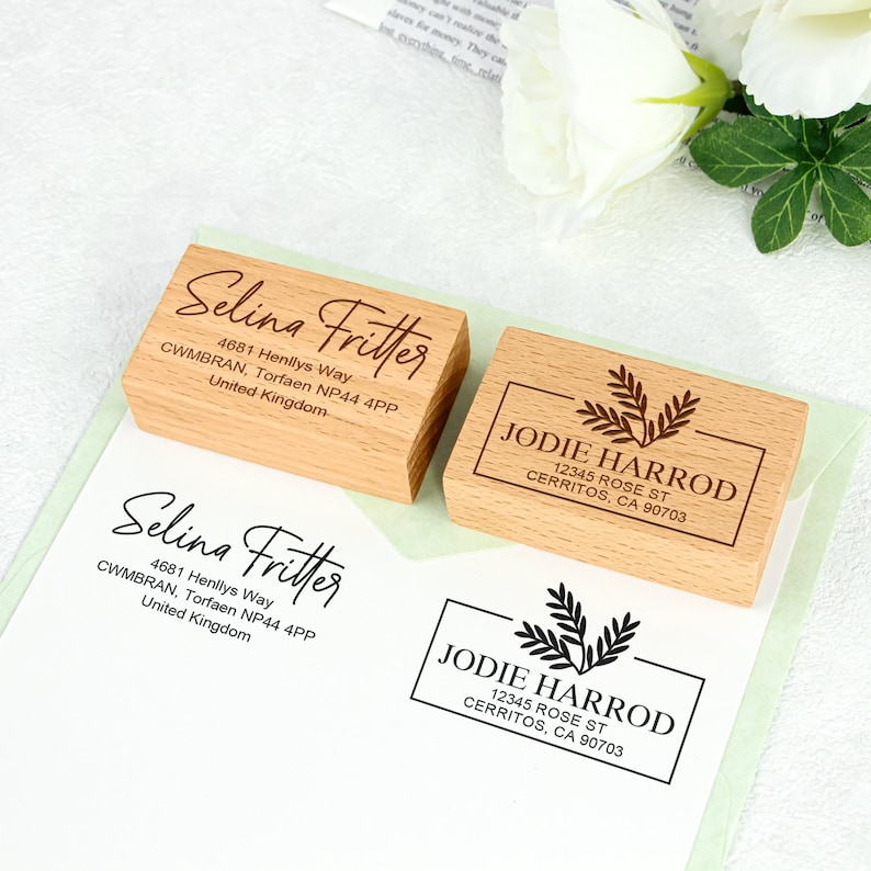 May include: Two wooden return address stamps. The first stamp is for Selina Fritter with her address and the second stamp is for Jodie Harrod with her address and a leafy design.