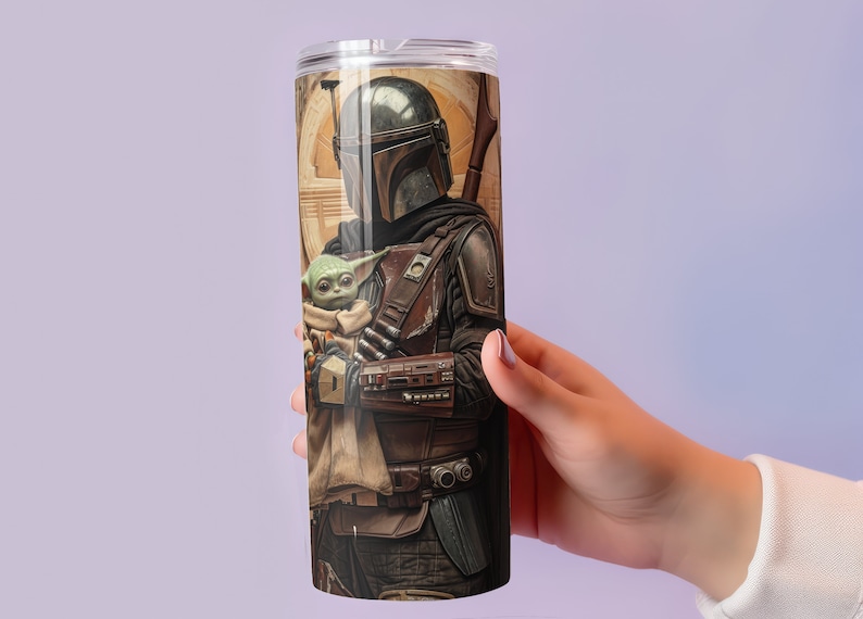 Puede incluir: Un vaso de acero inoxidable con una imagen colorida de un personaje mandaloriano sosteniendo una peque&ntilde;a criatura verde. La imagen est&aacute; impresa en todo el vaso.