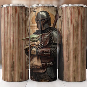 Puede incluir: Un vaso de acero inoxidable con un gr&aacute;fico de un personaje mandaloriano sosteniendo una peque&ntilde;a criatura verde. El fondo es un patr&oacute;n de veta de madera con rayas rojas y blancas.