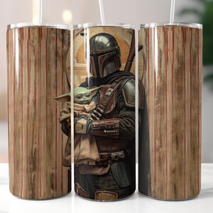 Puede incluir: Un vaso de acero inoxidable con un dise&ntilde;o de rayas marrones y rojas. El vaso presenta un gr&aacute;fico de un personaje mandaloriano sosteniendo una peque&ntilde;a criatura alien&iacute;gena verde.