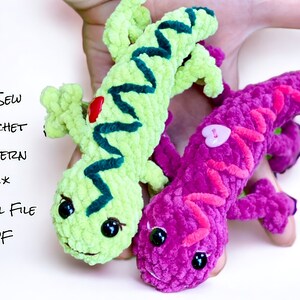 以下が含まれることがあります： 2匹のぬいぐるみのかぎ針編みトカゲのおもちゃ。1匹はライムグリーンで濃いティールアクセントと赤い斑点、もう1匹は紫でピンクのアクセントとハート型のボタンが付いています。画像には「No Sew Crochet Pattern」と「Digital File PDF」という文字が含まれています。