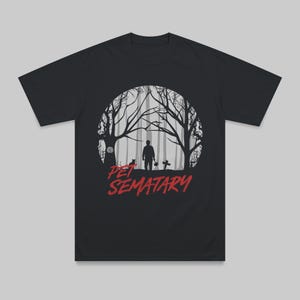 Black unisex t-shirt laid flat featuring a design inspired by Pet Sematary. Dark retro horror aesthetic referencing the Stephen King classic.