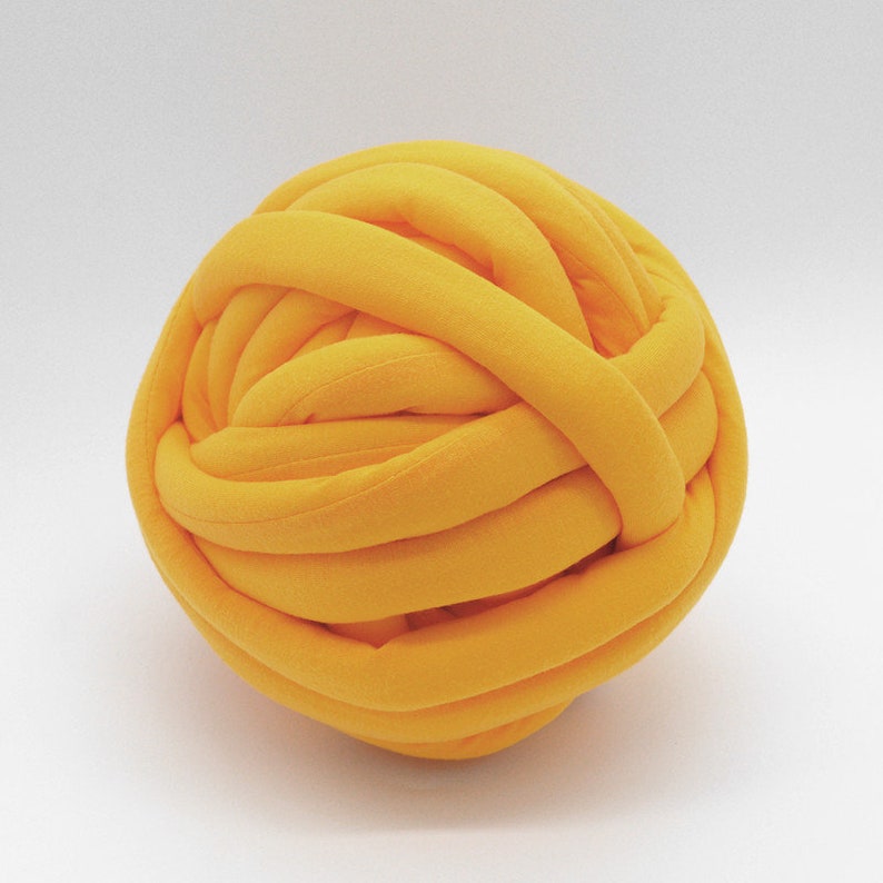 May include: A large, bright yellow ball of yarn made from thick, soft fabric. The yarn is tightly wound into a ball shape.