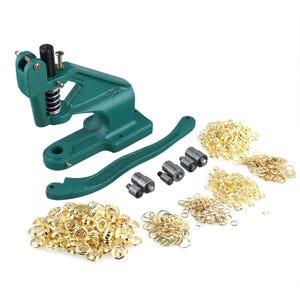May include: Green metal grommet setting tool with a lever and four different sized dies. The tool is surrounded by a variety of gold grommets and eyelets.