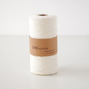 May include: A white cotton rope, wound into a roll, with a brown paper label that reads "SHEweave".