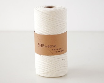 Könnte beinhalten: Ein weißes Baumwollseil, zu einer Rolle gewickelt, mit einem braunen Papieretikett mit der Aufschrift "SHEweave".
