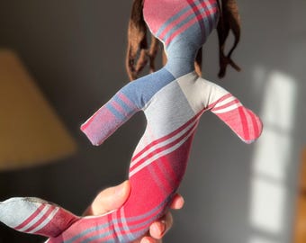 May include: A handmade mermaid doll with a plaid pattern in red, white, and blue. The doll has brown yarn hair and a whimsical design. The doll is made of soft fabric and is a unique, handcrafted item.