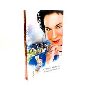 May include: A hardcover book titled "Miss Potter The Novel" featuring a woman's face and a cartoon rabbit. The cover has a blue and white background with the author's name, Richard Maltby Jr., and the text "Now a Major Motion Picture."