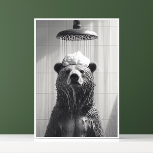 Op de afbeelding: Een zwart-witfoto van een beer die doucht. De beer staat in een douchecabine met water en zeepbellen die over zijn hoofd stromen. De beer heeft een serieuze uitdrukking op zijn gezicht.
