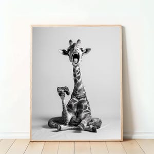 Könnte beinhalten: Schwarz-Weiß-Druck in einem Rahmen, der eine Giraffe zeigt, die im Schneidersitz sitzt, einen Videospiel-Controller hält und den Mund weit geöffnet hat. Die Giraffe ist das Hauptmotiv, vor einem neutralen Hintergrund, was ein humorvolles und modernes Kunstwerk ergibt.