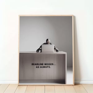 Puede incluir: Una impresión enmarcada de una tortuga sentada en un escritorio con una computadora portátil, el texto "DEADLINE MISSED... AS ALWAYS." está en el escritorio.