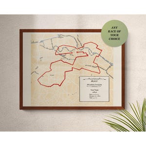 May include: Framed map print with a red marathon route overlaying a beige city map. The print includes a green circle with the text "ANY RACE OF YOUR CHOICE" and a small box with the text "ANY MARATHON".