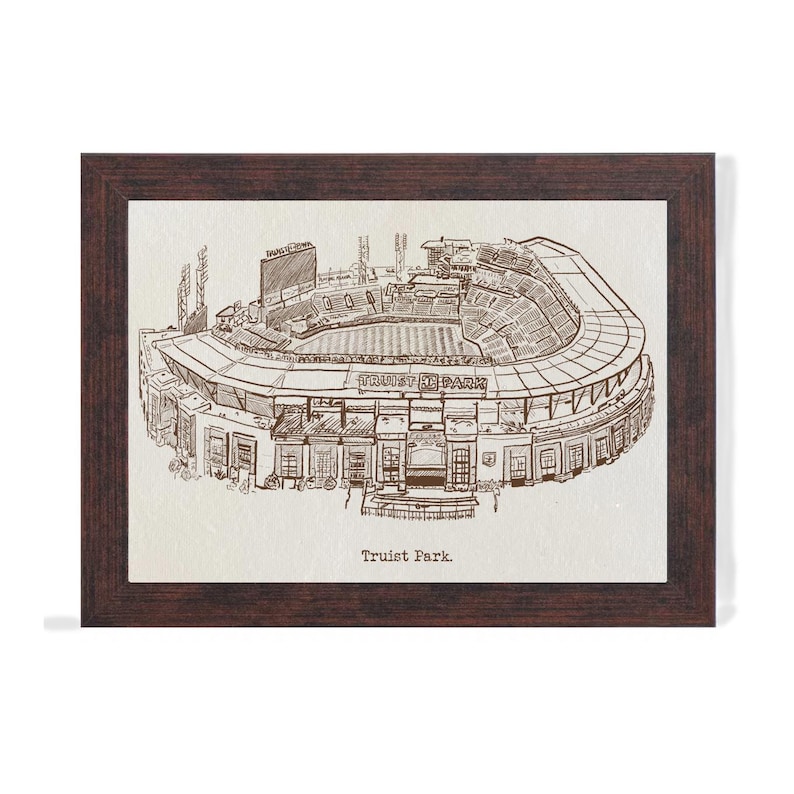 May include: A framed print featuring a detailed sketch of Truist Park, a baseball stadium. The artwork is in sepia tones, showcasing the stadium's architecture, including the seating, field, and scoreboard. The frame is a dark brown color.