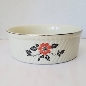 Peut inclure: Un plat à four en céramique blanche avec un bord argenté et un motif floral noir et orange. Le plat est à nervures.