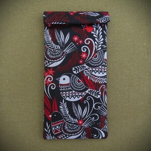 May include: Black fabric pouch with a red and white bird pattern. The birds are stylized and have geometric designs. The pouch is folded over at the top.