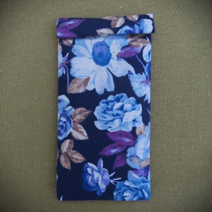 May include: A blue floral fabric pouch with a white and blue floral pattern. The pouch is folded over at the top and has a seam down the center.