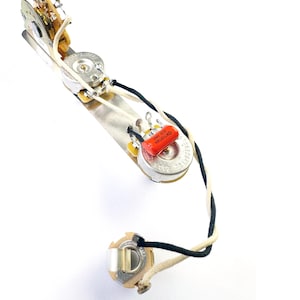 May include: Guitar wiring harness with two potentiometers, a capacitor, and a jack. The wiring is white and black.