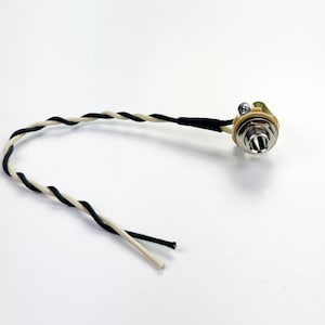 May include: A close-up of a black and white guitar cable with a gold-colored jack on the end.