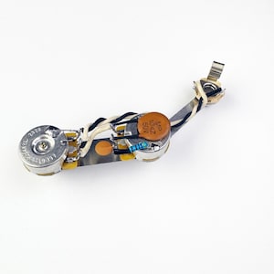May include: A silver-colored guitar wiring harness with a brown capacitor labeled "MP 1042 50V", a black and blue resistor, and a white and brown wire.