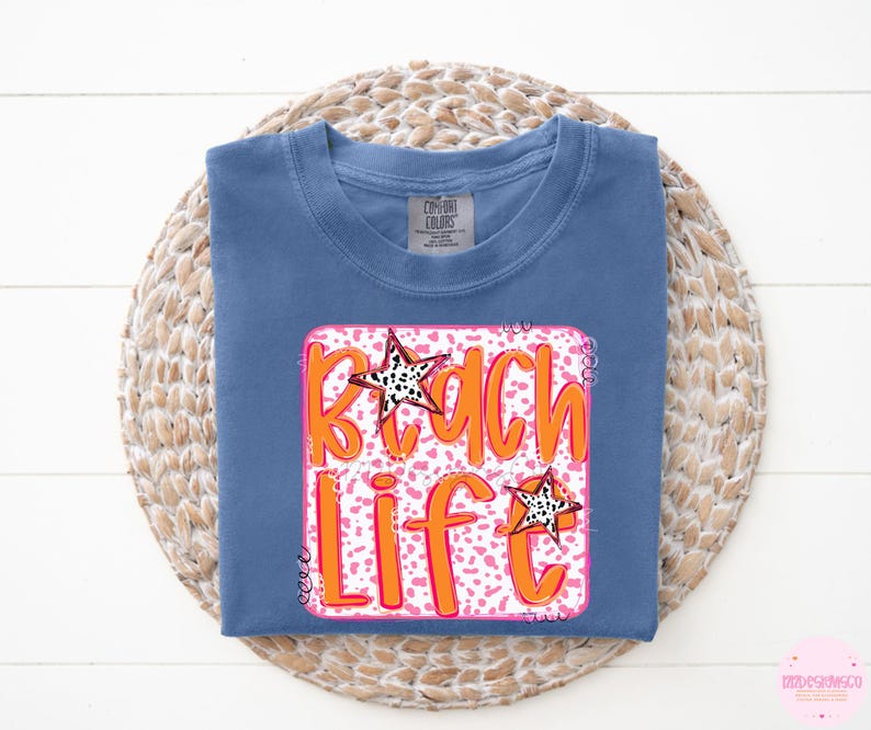 Puede incluir: Una camiseta azul con un gr&aacute;fico rosa y naranja que dice "Beach Life" con un dise&ntilde;o de estrella.
