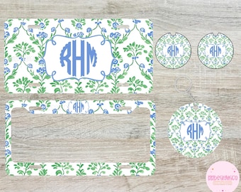 May include: A set of personalized car accessories featuring a blue and green floral pattern. The set includes a license plate frame, two round car coasters, and a key chain. The monogram "RHM" is featured on each item.