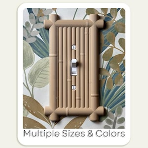 Puede incluir: Una cubierta de interruptor de luz de estilo bambú de color beige con un interruptor blanco y dos orificios para tornillos. La cubierta es rectangular con un diseño acanalado vertical. El fondo es un papel pintado floral. El texto en la parte inferior dice "Multiple Sizes & Colors."