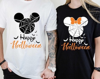 May include: A couple wearing matching black and white t-shirts with a Mickey Mouse and Minnie Mouse design. The shirts say "Happy Halloween" in orange text.