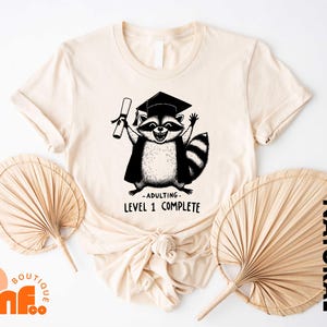 a t - shirt with a picture of a raccoon wearing a graduation cap