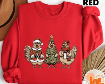May include: A red sweatshirt featuring three chickens dressed for Christmas. One chicken is dressed as Santa, another as a Christmas tree, and the third holds a gift. The word "RED" is printed at the top.