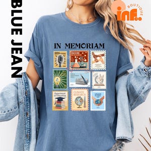 A woman wearing a blue t-shirt with a collage of various postage stamps printed on it, along with a denim jacket.