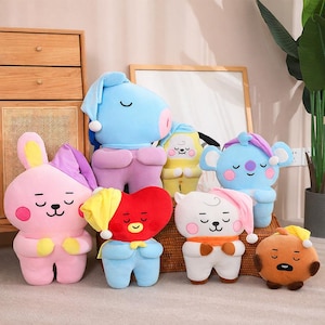 May include: A collection of plush toys in various shapes and colors, including a pink bunny, a blue koala, and a red heart. Each toy has a sleeping cap and closed eyes, suggesting a bedtime theme. The toys are soft and cuddly.