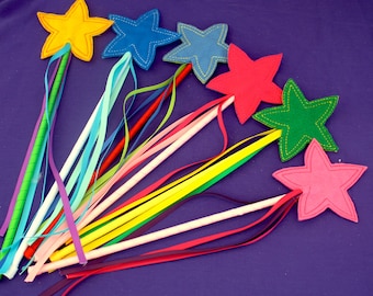 May include: A collection of colorful star-shaped wands with ribbon streamers. Each wand features a different colored star, including yellow, blue, red, green, and pink, with coordinating ribbon accents. The wands are set against a purple background.