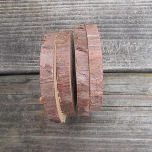 May include: Four round wood slices stacked on top of each other. The wood is a light brown color and has a natural bark edge.