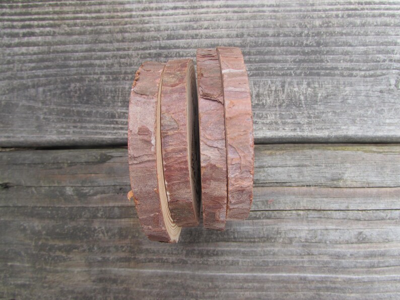 May include: Four round wood slices stacked on top of each other. The wood is a light brown color and has a natural bark edge.