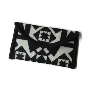 May include: Black and white geometric patterned clutch purse with a fold-over flap.