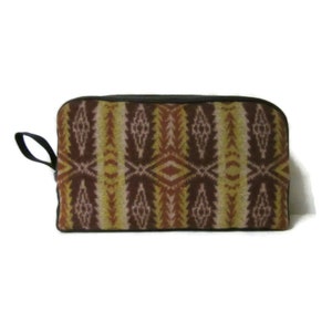 May include: A brown, yellow, and pink patterned toiletry bag with a black zipper and a black strap.