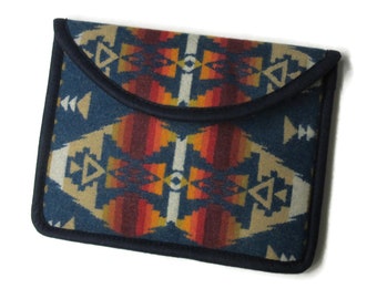 May include: A blue and orange patterned fabric clutch with a flap closure. The fabric has a geometric design with a southwestern style.
