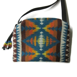May include: A small teal, orange, and brown patterned crossbody bag with a black strap and a beaded tassel.