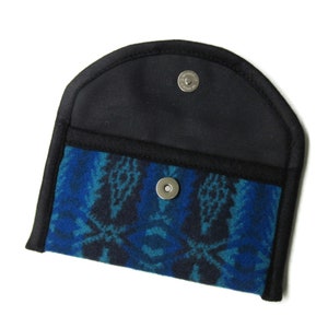 May include: A small, black wallet with a blue and black patterned fabric lining. The wallet has a snap closure and a rounded top.