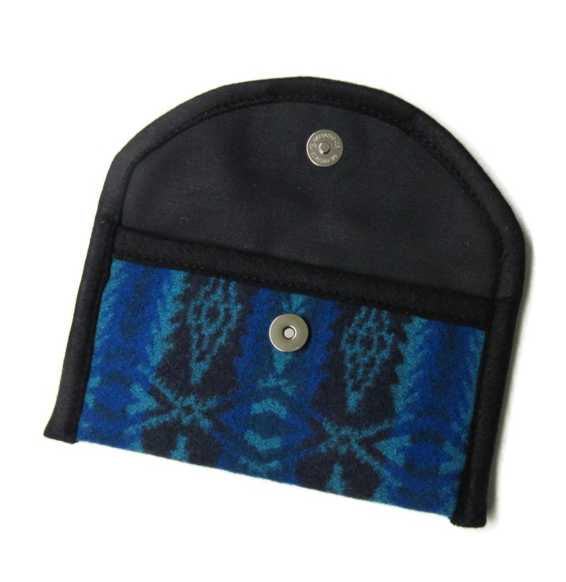 May include: A small, black wallet with a blue and black patterned fabric lining. The wallet has a snap closure and a rounded top.