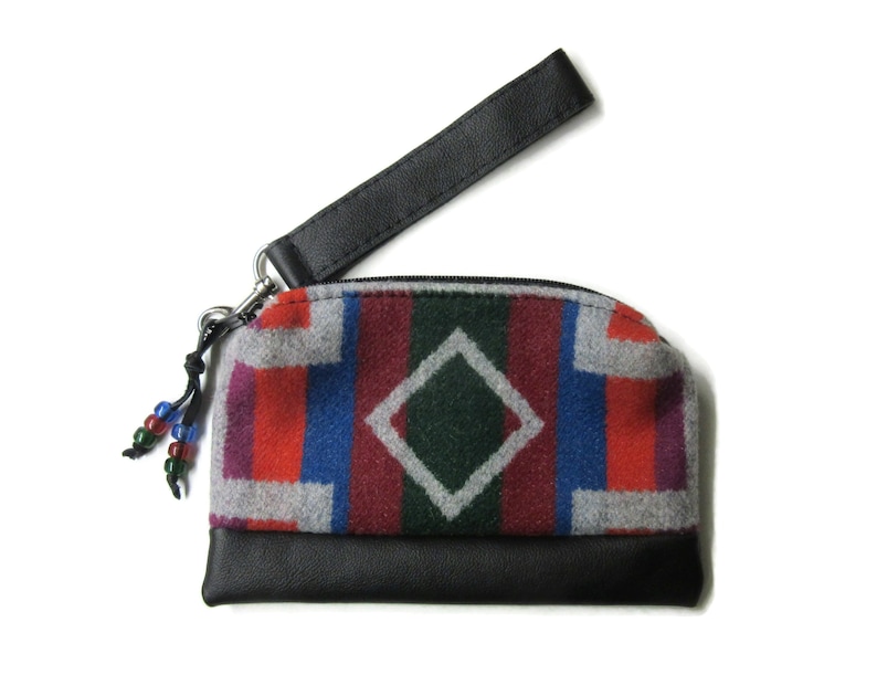 Pu&ograve; includere: Una piccola pochette con cerniera nera e grigia con un cinturino in pelle nera e un motivo geometrico colorato. La pochette &egrave; realizzata in un materiale morbido e soffice.