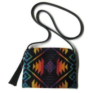May include: A small black crossbody bag with a rainbow geometric pattern and a black tassel. The bag has a black adjustable strap.