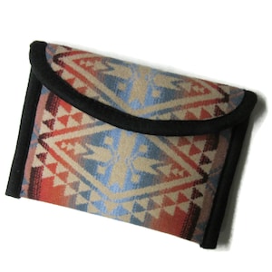 May include: A small, rectangular wallet with a black trim and a colorful geometric pattern in shades of red, orange, blue, and beige.