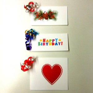 May include: Three gift tags with colorful ribbon embellishments. The top tag features a green and red holiday wreath. The middle tag says "Happy Birthday!" in rainbow letters. The bottom tag has a red heart.